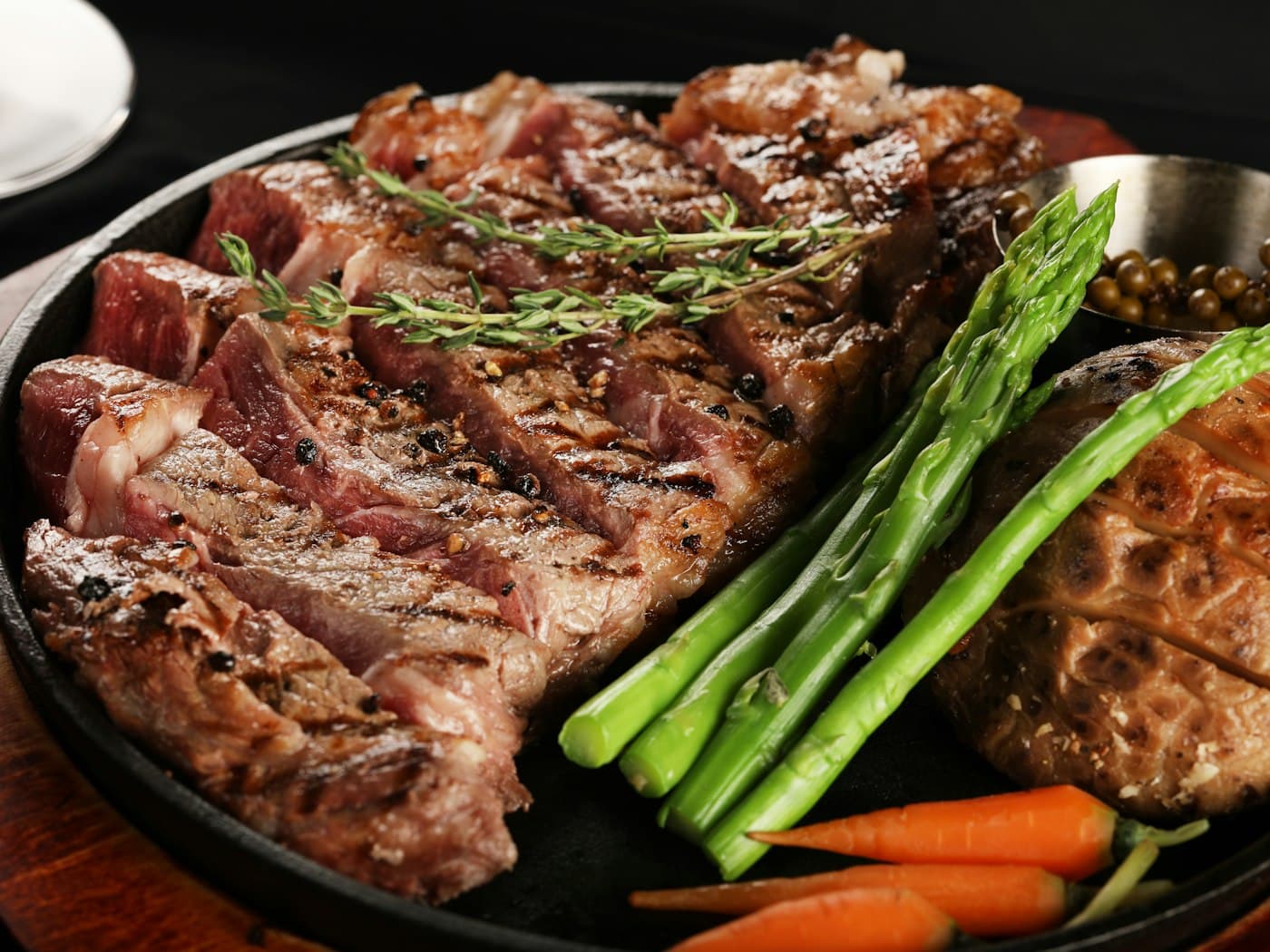 A charcoal-grilled steak with seasonal vegetables on a cast-iron skillet